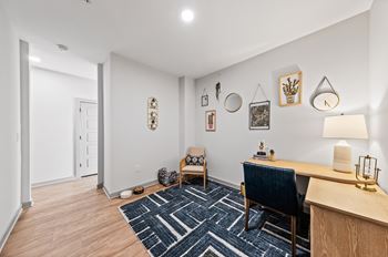 A room with a blue chair and a desk with a lamp on it.